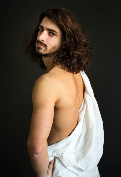 Foto von gutaussehenden Kerl mit lockigem Haar in einem weißen Vorhang halb gedreht - Foto, Bild