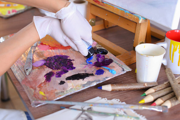 Художник экструдирует краску из трубок на палитре для смешивания цветов t
 - Фото, изображение