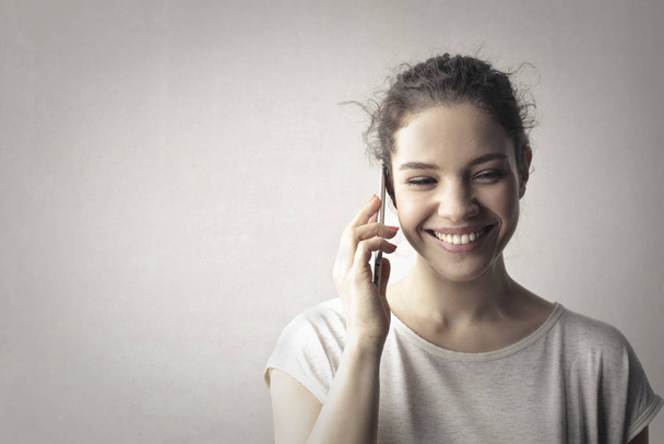 Woman smiling while taliking on phone - Foto, imagen