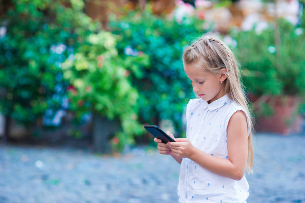 Adorable toddler girl with smart phone in Europe city outdoors - Photo, Image