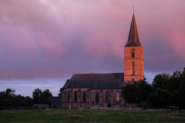 вечірнє сонце освітлює церковну вежу
 - Фото, зображення
