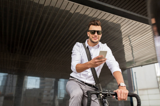 man with bicycle and smartphone on city street - Фото, зображення
