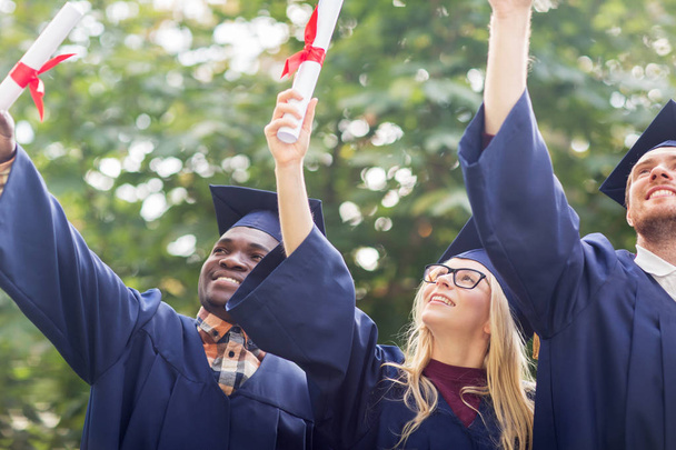Glückliche Studenten in Mörteltafeln mit Diplomen - Foto, Bild