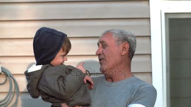 Grandfather and grandson talking, smiling, having fun, looking to camera outdoor. Old man holding on hand little boy. 4K - Footage, Video