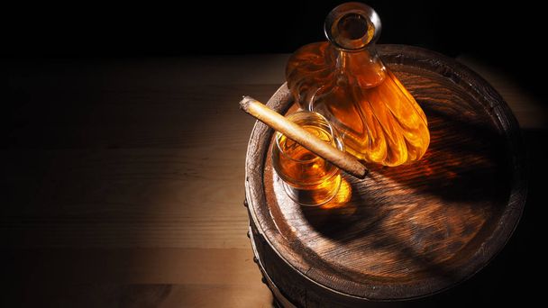 Glass of cognac with barrel on wooden backgroun - Foto, Imagen
