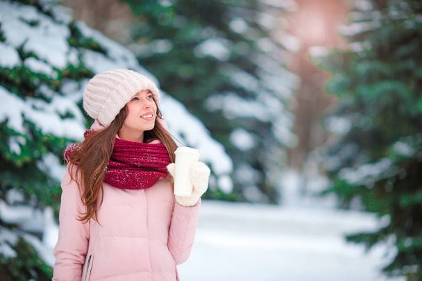 Beautiful girl with coffee to go outdoors on beautiful winter snow day - 写真・画像