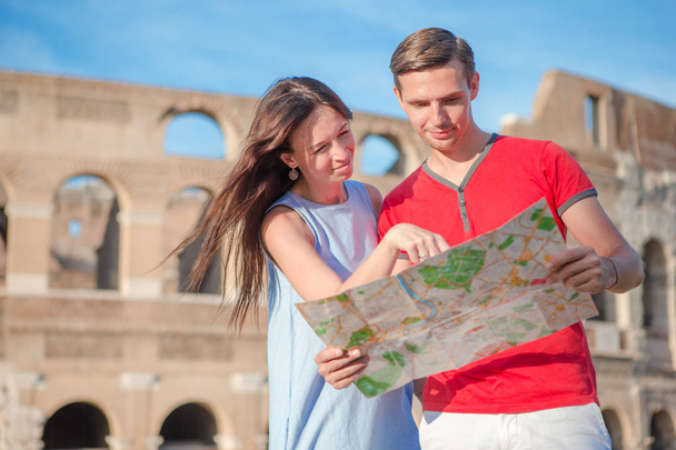 Giovane coppia turistica che viaggia in vacanza all'aria aperta sorridendo felice. Famiglia caucasica con mappa sullo sfondo del Colosseo
 - Foto, immagini
