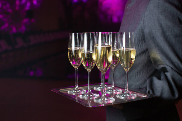 Ober serveren champagne op een dienblad - Foto, afbeelding
