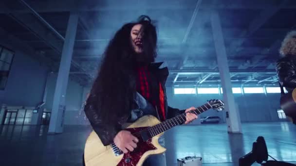 ausdrucksstarke asiatische Frau spielt Gitarre im Hangar - Filmmaterial, Video