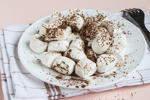 Marshmallows spolverato con cacao su piastra bianca
 - Foto, immagini