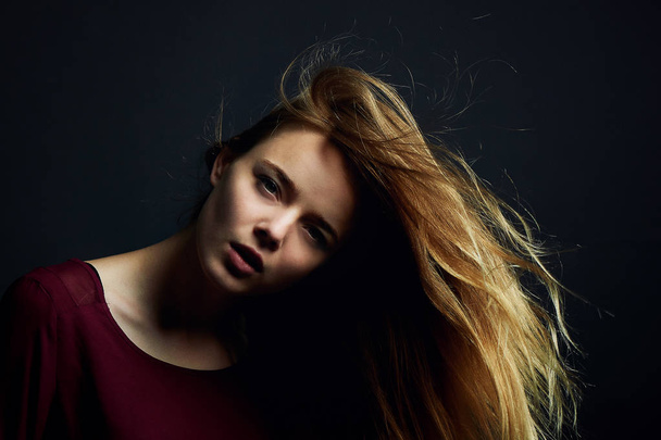 The hand in her hair. Beautiful young girl dancing. Hair flying. Shooting in Studio on dark background - Foto, immagini
