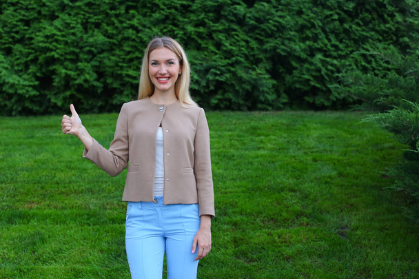 Energetic young woman shows gesture thumbs up at arms length an - Photo, Image