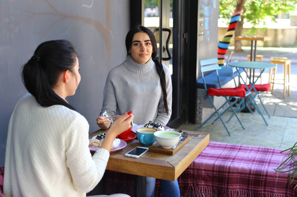 Три красивые женские улыбки в кафе, разговаривают, рассказывают секреты, едят, г
 - Фото, изображение