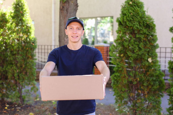Young Courier Man Carring Order in Hands, Smiling at Camera and - Фото, зображення