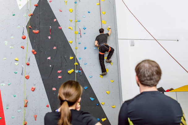 Fit Friends on the artificial climbing wall indoors discussing tactics of bouldering - Photo, Image