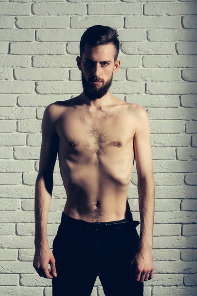 slim bearded man with thin bare torso on brick background - Foto, afbeelding
