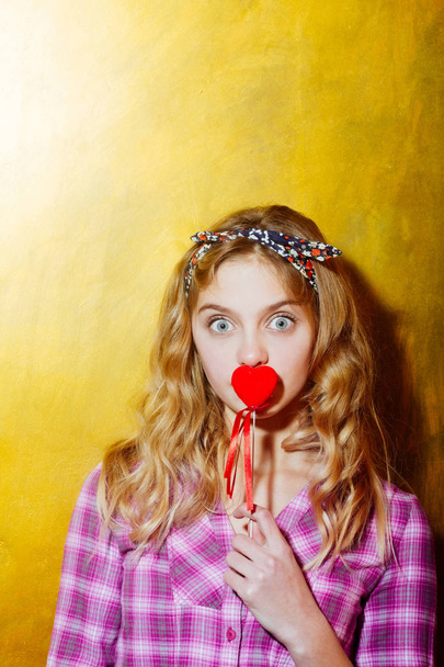 Surprised pretty girl with red heart on stick - Photo, image