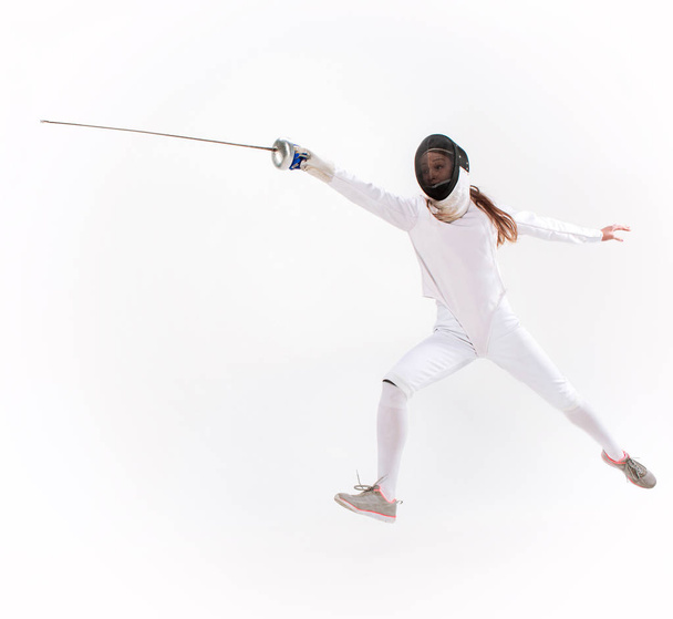 Man wearing fencing suit practicing with sword against gray - Zdjęcie, obraz
