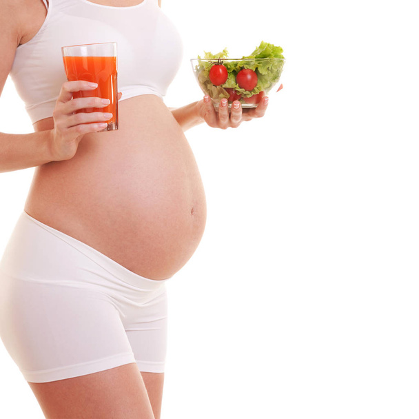 Pregnant woman holding salad and glass with juice. Isolated on white background. Nutrition and diet during pregnancy. Close up. Motherhood, pregnancy, people and expectation concept - Photo, Image