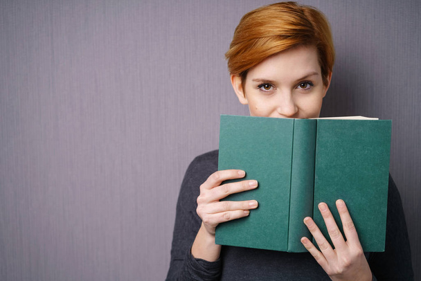 Woman covering mouth with book - Photo, image