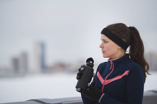 Jonge vrouw joggen buiten bewolkt winterdag - drinkwater - Foto, afbeelding