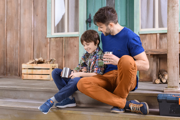man and boy sitting on porch - Фото, изображение