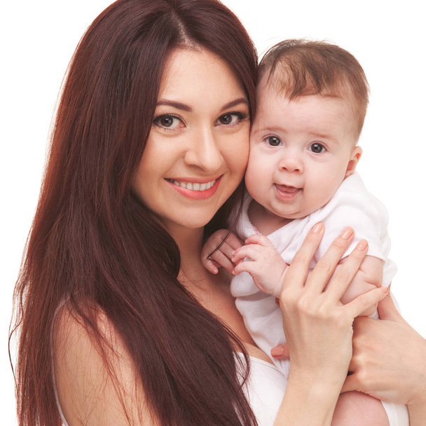 Ευτυχισμένη οικογένεια, μητέρα που κρατάει το μωρό της, απομονώνονται σε λευκό φόντο. Κοντινό πλάνο πορτρέτο της μητέρας και χαριτωμένο μωρό σε λευκό χρώμα. Ευτυχής όμορφη γυναίκα εκμετάλλευση γλυκό μωρό. Άτομα, η μητρότητα και η οικογένεια έννοια - Φωτογραφία, εικόνα
