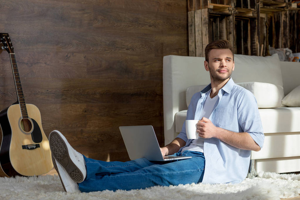 Young man with laptop and cup - Photo, Image
