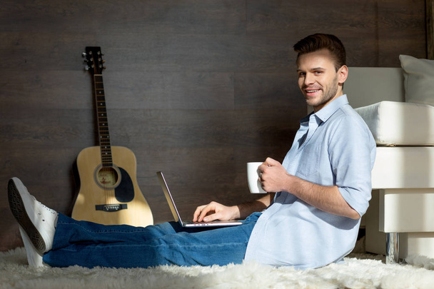 Fiatal férfi laptop és kupa - Fotó, kép
