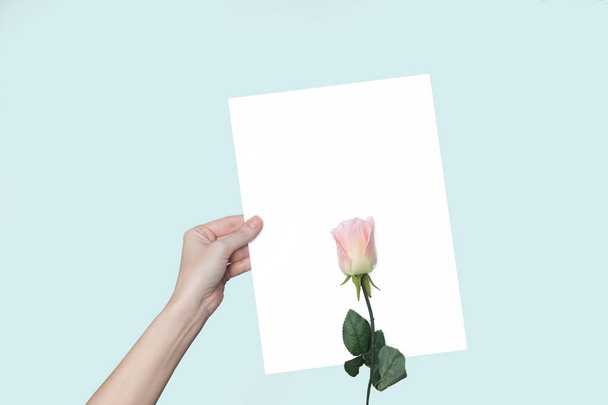аркуш паперу в руці і квітка, троянда, на фоні
 - Фото, зображення