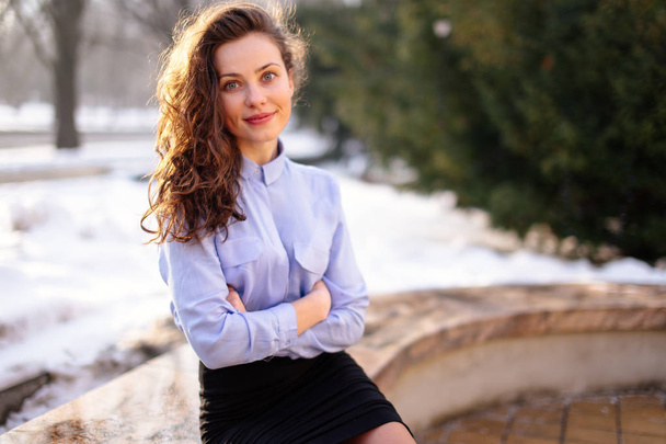 Woman sitting on the bench with park background and smile to cam - Фото, изображение