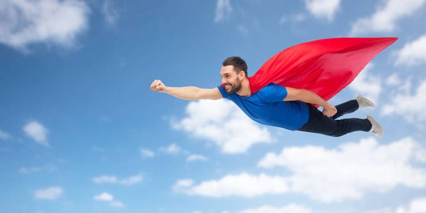 happy man in red superhero cape flying on air - Фото, изображение