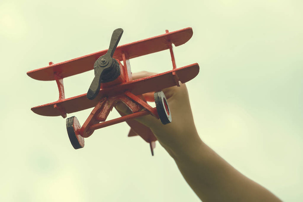 木製の手作りの飛行機を持っている子手 - 写真・画像