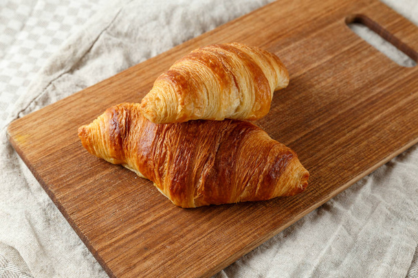Deliciosos croissants franceses recém-assados em uma placa de corte de madeira
. - Foto, Imagem