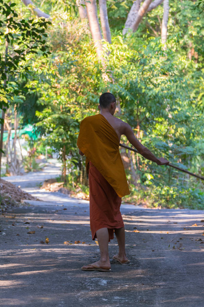 Thai monk sweeping a temple floor - Foto, imagen