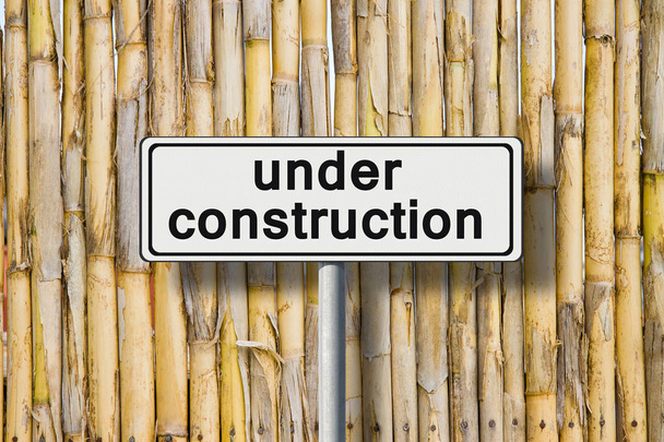 Строится на дорожном знаке у бамбукового забора
  - Фото, изображение