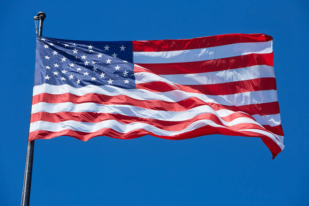 American or USA flag in wind, clear blue sky - Zdjęcie, obraz