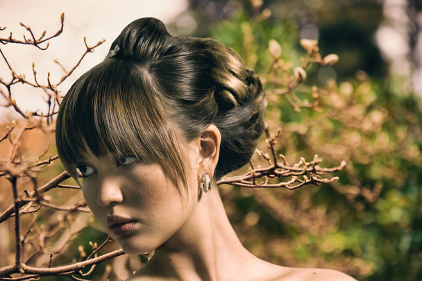 Beautiful bride with gorgeous hairdo looking aside and autumn branches - Foto, afbeelding