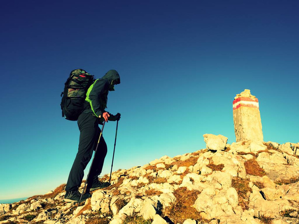 Turisti pylväät ja reppu kävellä vuoren huipulle. Viimeinen askel huippukokoukseen
 - Valokuva, kuva