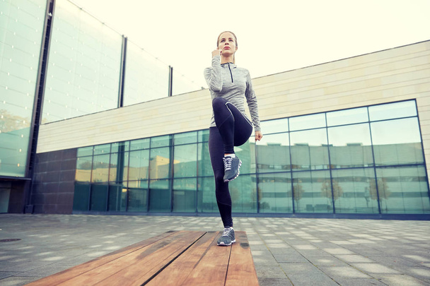 woman making step exercise on city street bench - 写真・画像