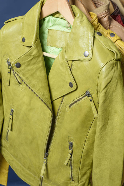Many colored  leather jacket hanging on rack on blue background - Zdjęcie, obraz