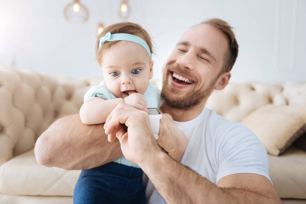 Joyful young bearded father playing with the daughter at home - Фото, зображення