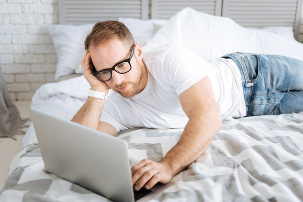 Pleasant bearded man using laptop at home - 写真・画像