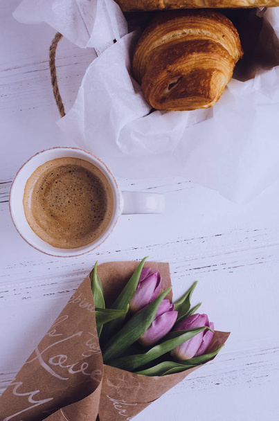 Cup of coffee with bouquet of pink tulips and croissant - 写真・画像