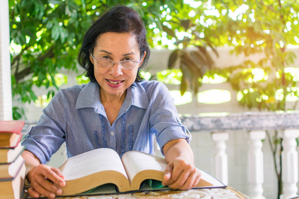 Μέσης ηλικίας γυναίκα διαβάζοντας ένα βιβλίο στο σπίτι - Φωτογραφία, εικόνα