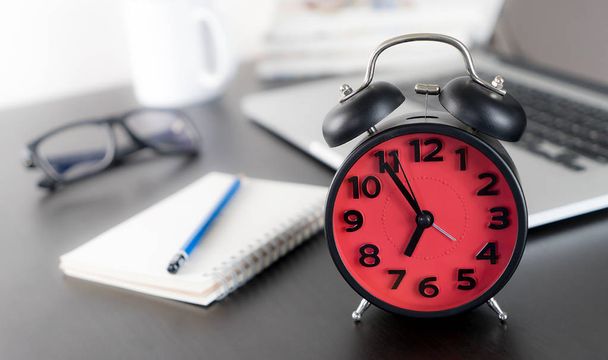 Relógio de alarme vermelho na mesa de escritório com computador
 - Foto, Imagem