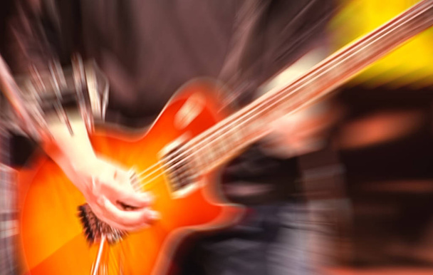 Nahaufnahme defokussiert verschwommenen Mann spielt Gitarre auf der Bühne eines Rockkonzerts mit Geschwindigkeit Bewegungsunschärfefilter - Foto, Bild