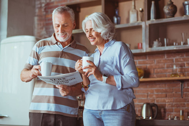 Positive aged couple reading daily press - Foto, Imagem