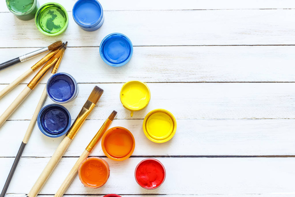 Paints and brushes on a white wooden background - Fotografie, Obrázek
