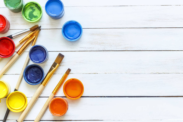 Paints and brushes on a white wooden background - Photo, image